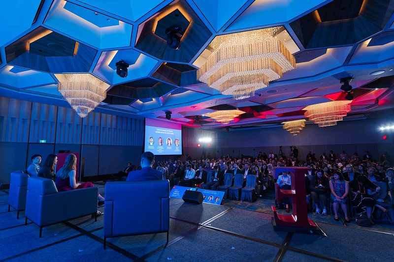 Empty ballroom staged for Future of Health Asia 2024 beneath red-lit chandeliers